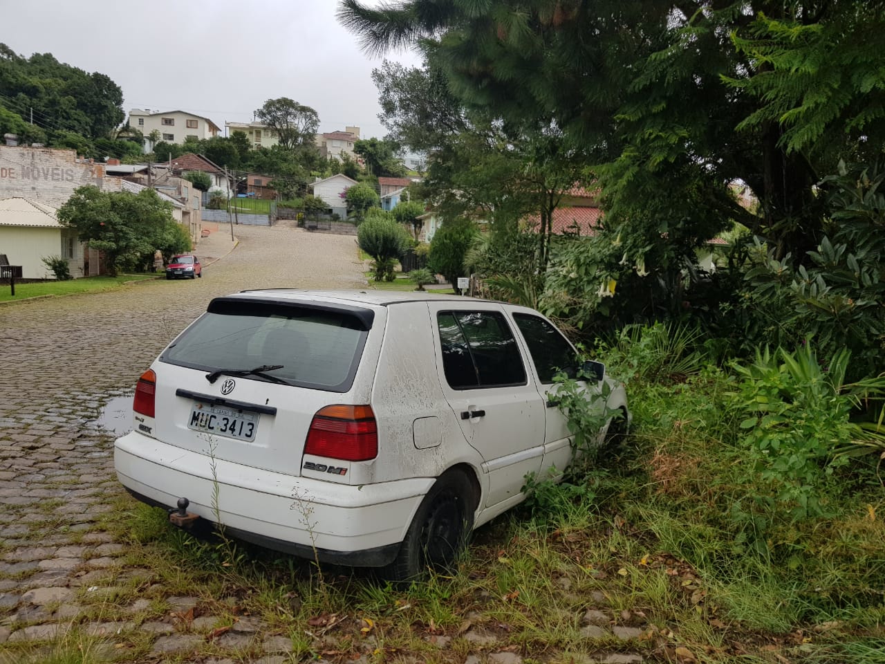 Carro com pneus furados e vidro quebrado impede limpeza do local e propicia crescimento de mato na rua